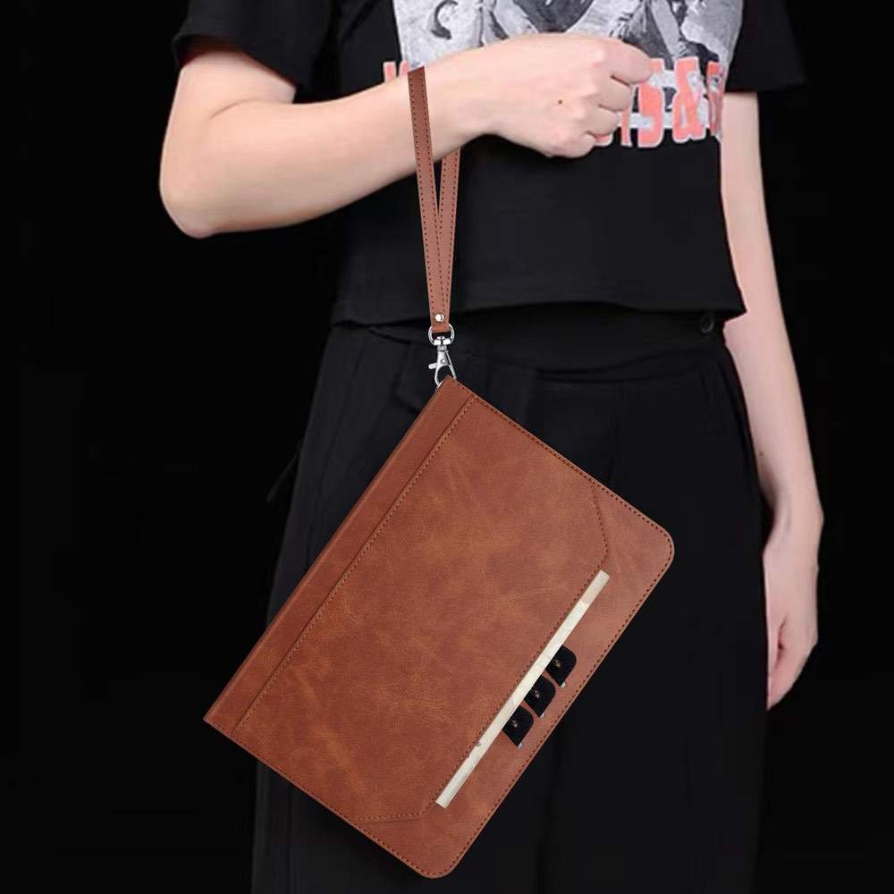 Brown leather clutch bag held by a person against a black background